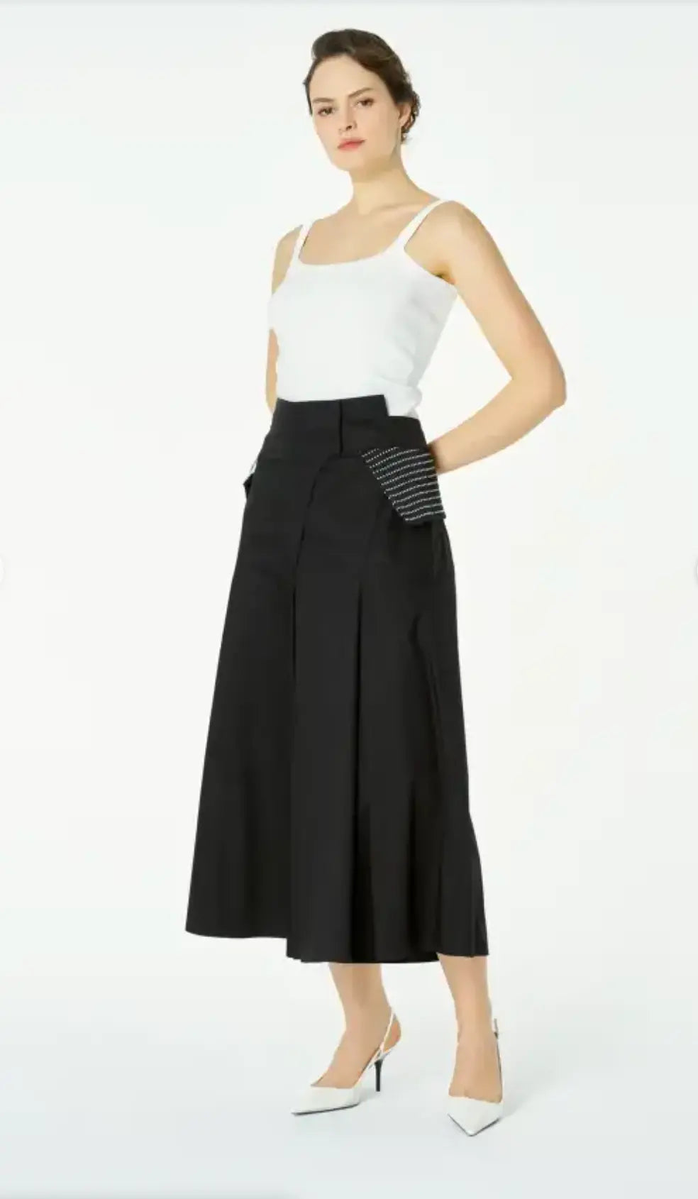 Woman wearing a white top and black high-waisted pants with a striped glove on a white background