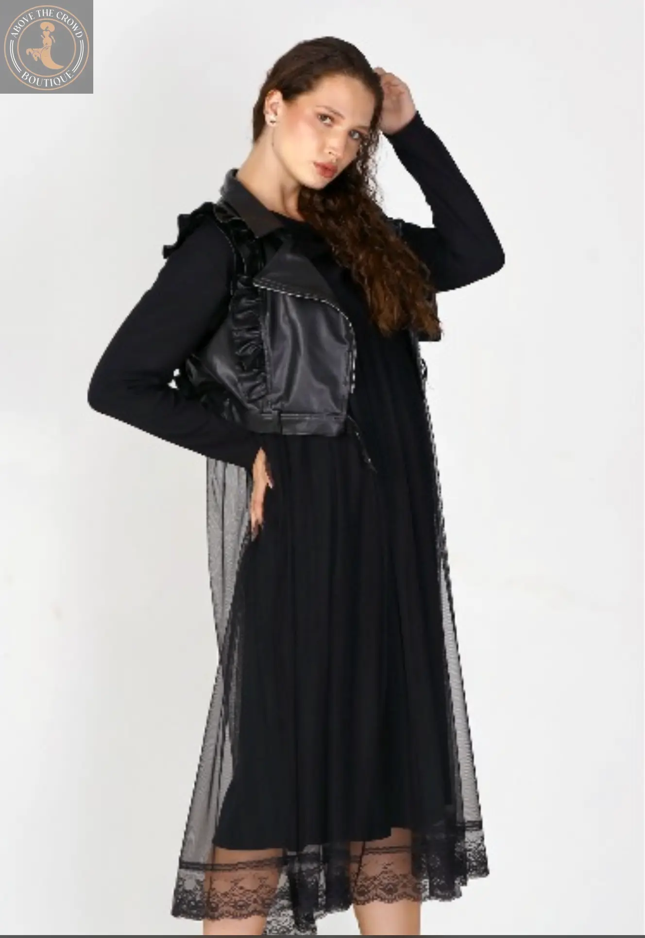 Woman wearing a black dress with sheer overlay on a white background