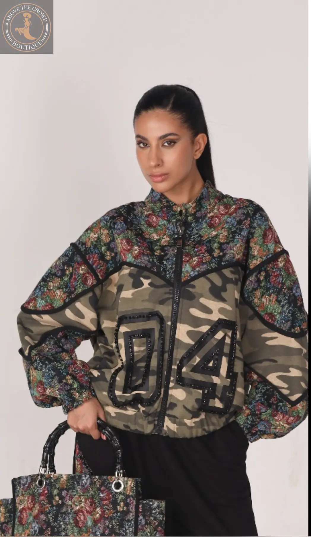 Woman wearing a floral and camouflage jacket with a plain background