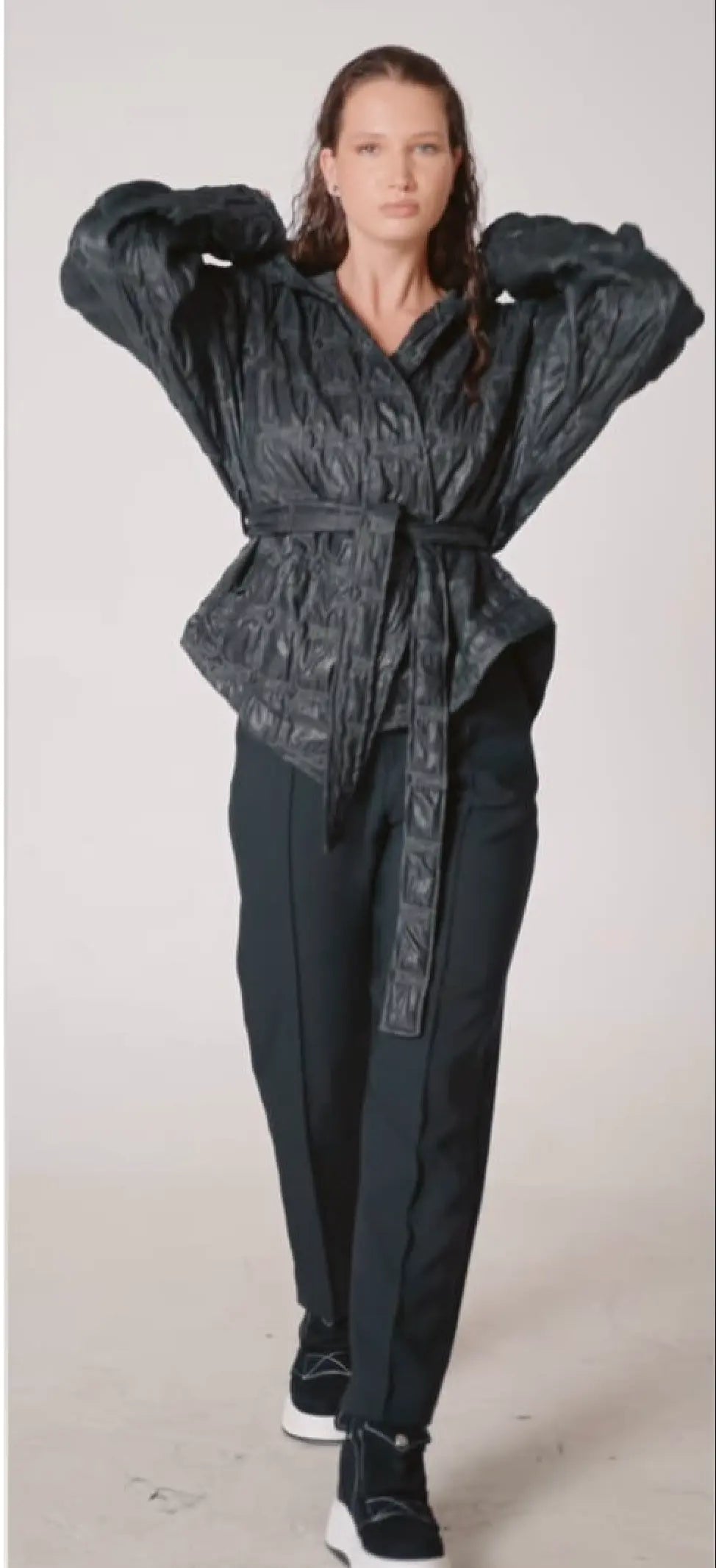 Person wearing a black textured jacket and pants on a white background