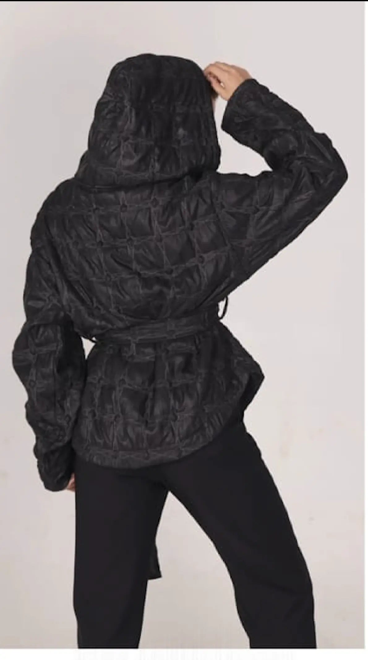 Person wearing a textured black jacket on a plain background
