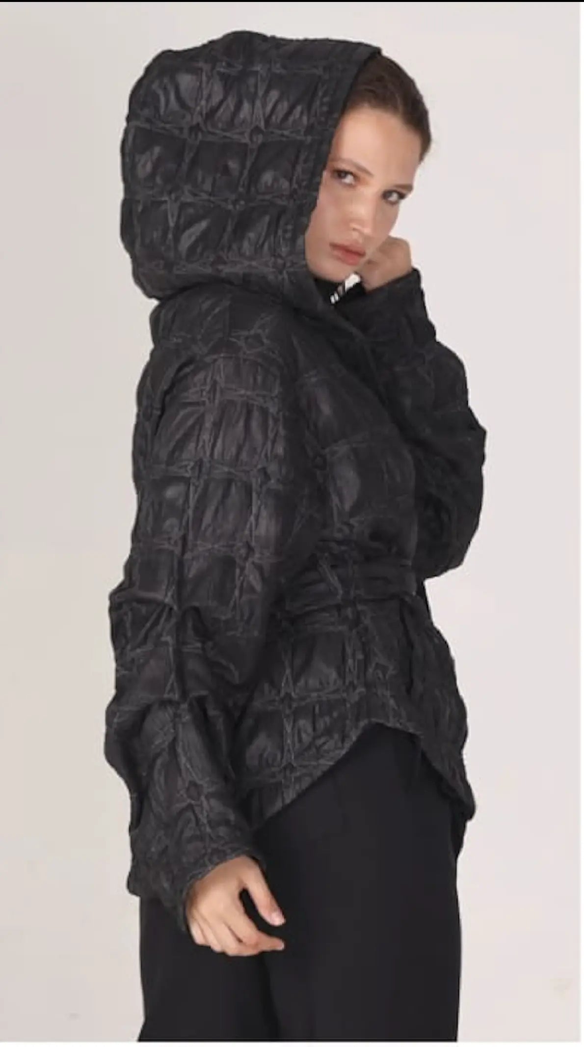 Person wearing a black textured hooded jacket on a white background